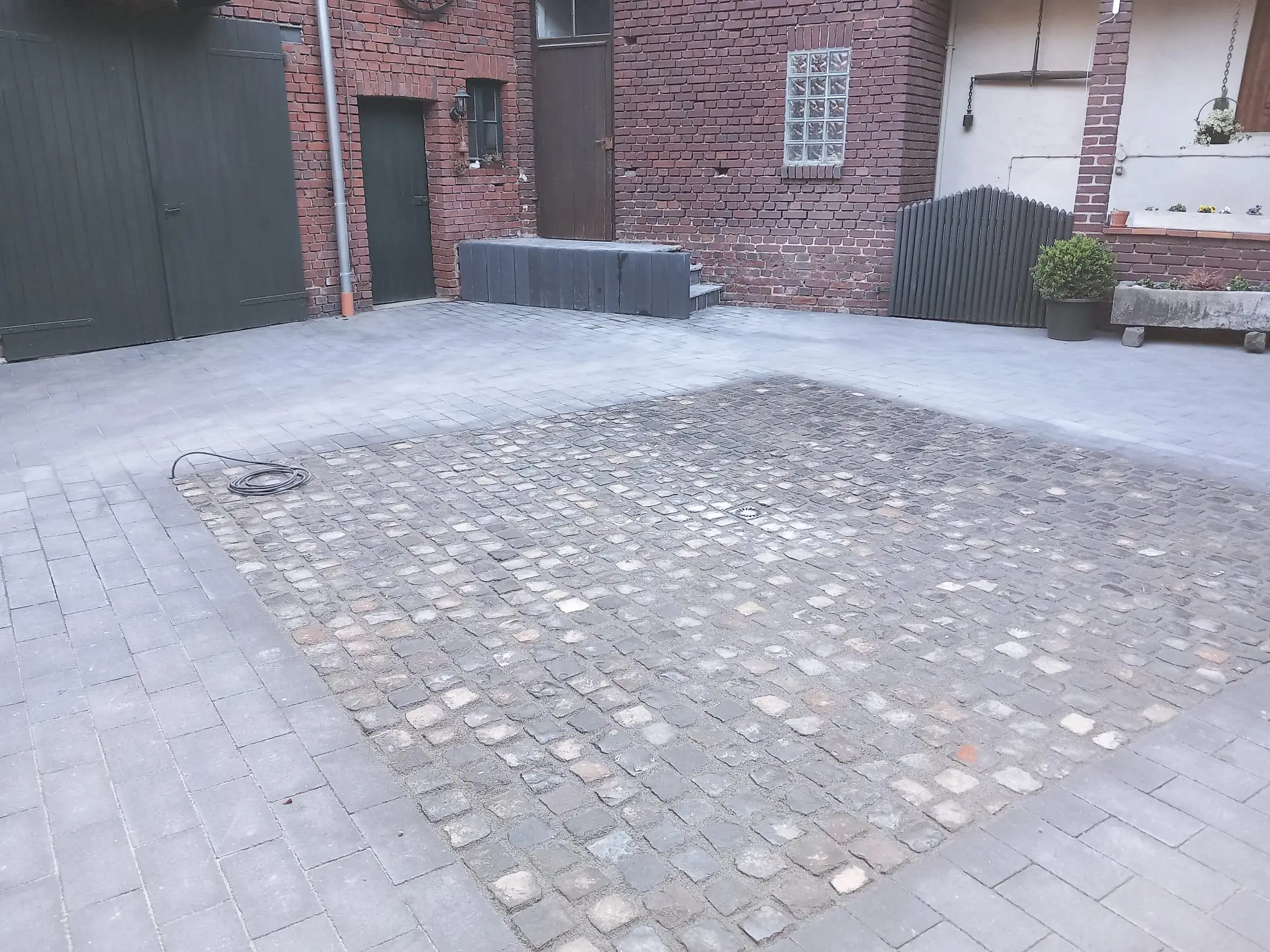 Innenhof mit einer rechteckigen Natursteinpflasterfläche in der Mitte